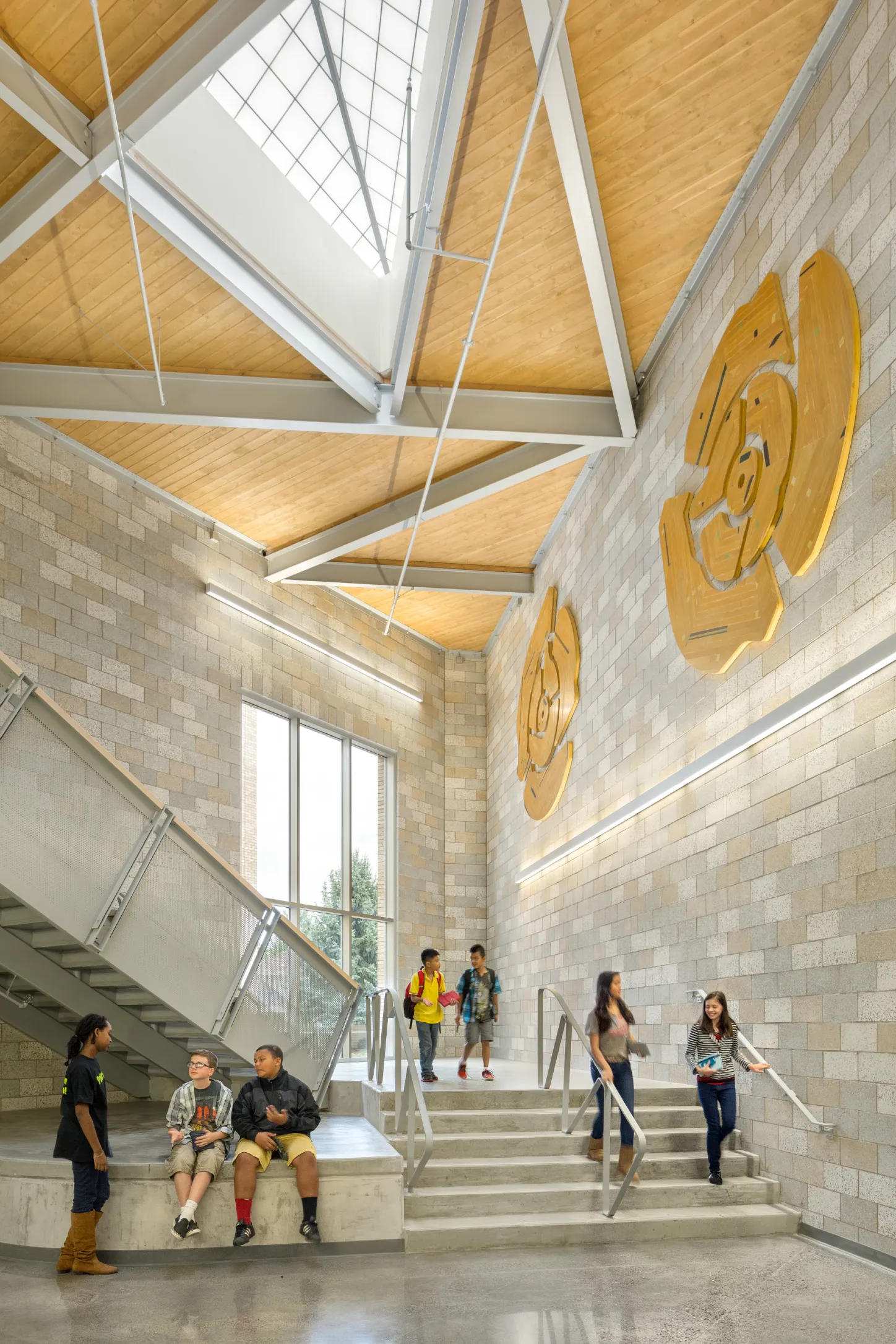 Students on a sunlit stairway framed by architectural concrete masonry walls